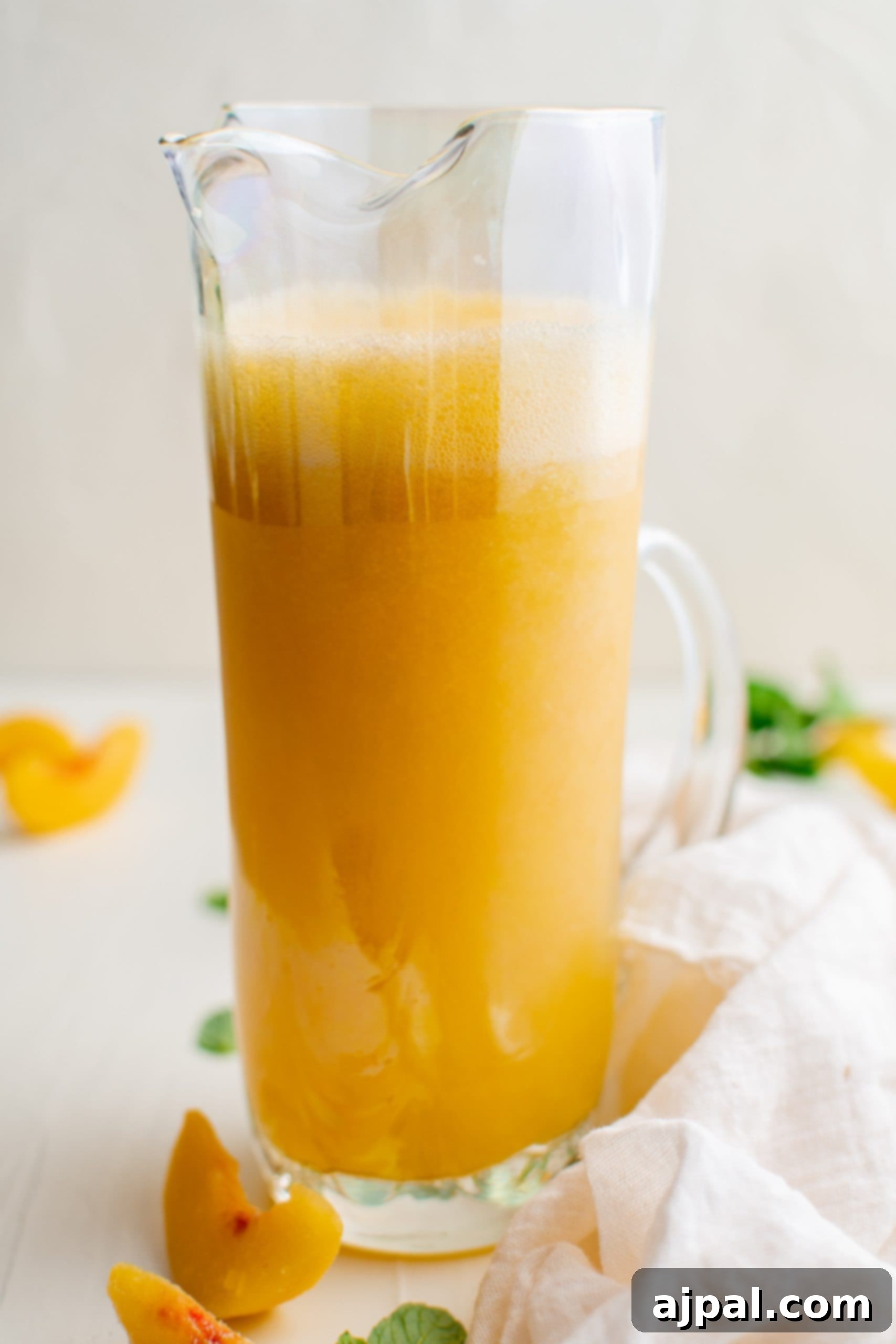 A large glass pitcher filled with homemade peach puree, ready to be mixed with sparkling wine for Bellinis.
