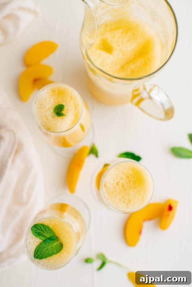A close-up shot of two peach bellinis in elegant champagne flutes, artfully garnished with fresh mint, sitting on a rustic wooden table.