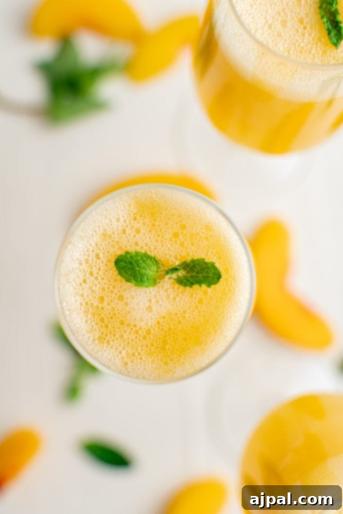Two elegant champagne flutes showcasing peach bellinis, each garnished with fresh mint sprigs, highlighting their refreshing appeal.