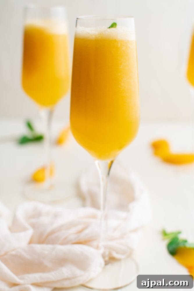 A single elegant champagne glass holds a perfectly crafted peach bellini, garnished with a sprig of fresh mint.