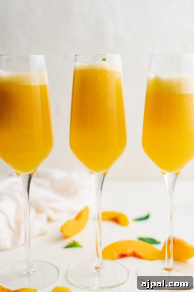Three elegant champagne flutes filled with vibrant peach bellinis, each garnished with a fresh sprig of mint, ready to be enjoyed.