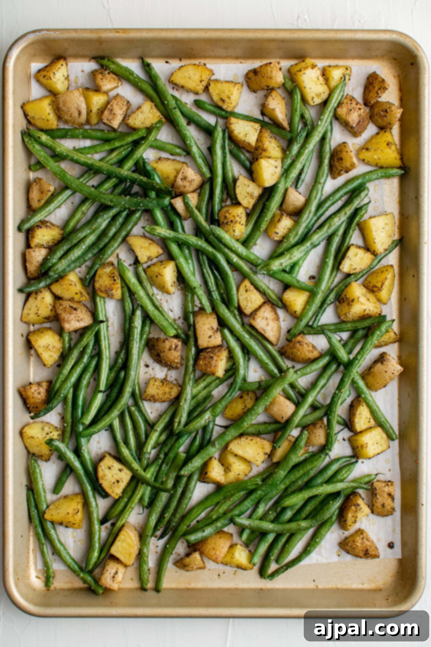 Savory Herb Roasted Green Beans and Potatoes 12 Oven-roasted green beans and potatoes on a baking sheet.