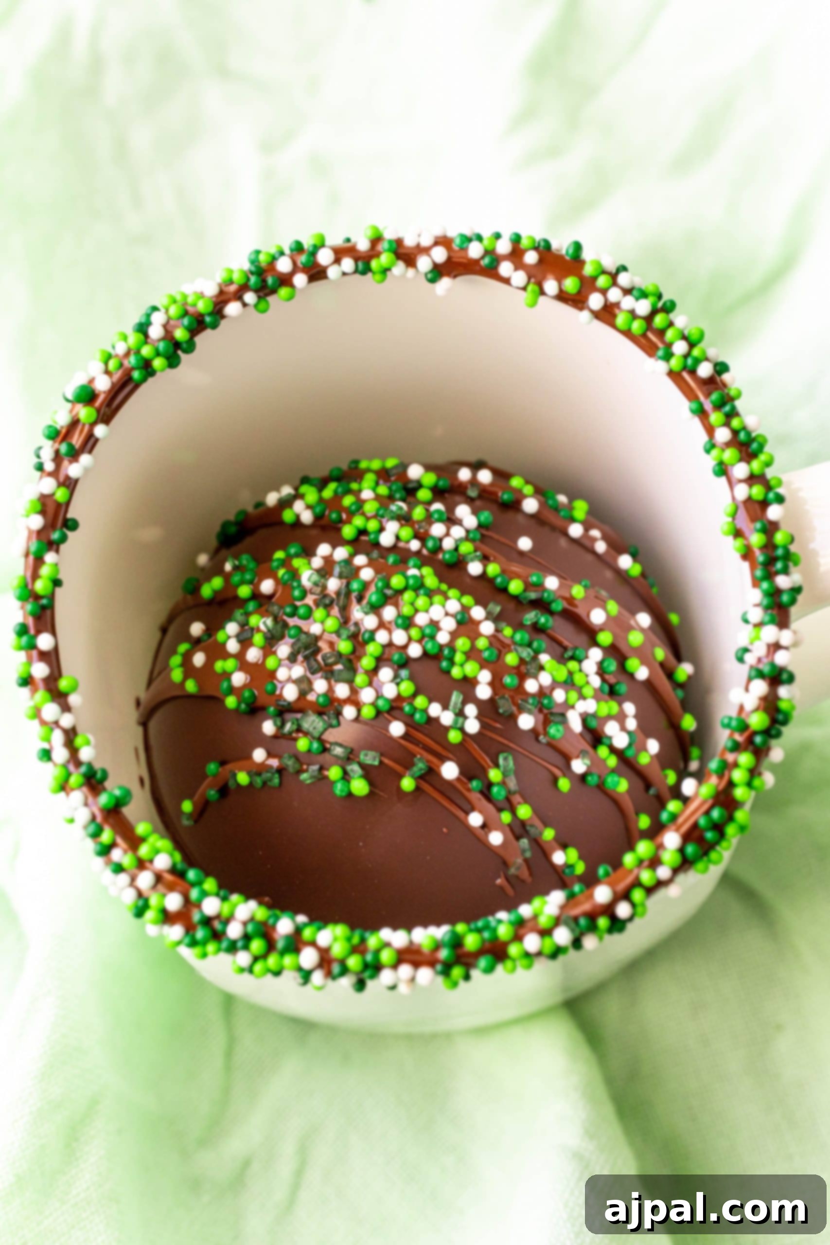 Irresistible Mint Hot Chocolate Bombs 13 mint hot chocolate bomb in a white mug with sprinkles on the rim.