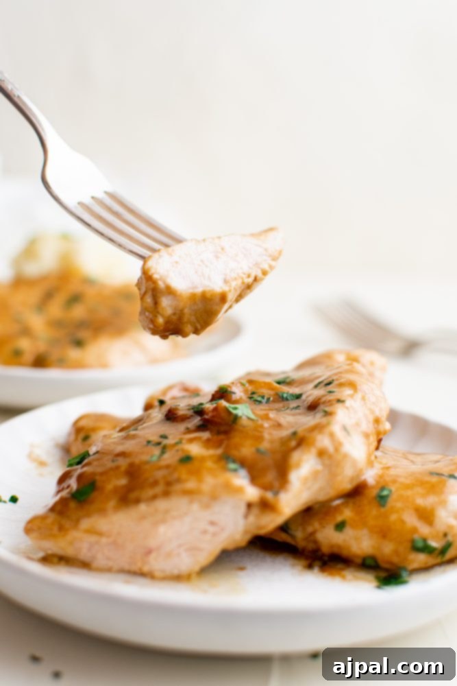 Creamy Garlic Chicken Made Simple 13 A fork lifts a piece of creamy garlic chicken, showing its rich sauce and parsley garnish