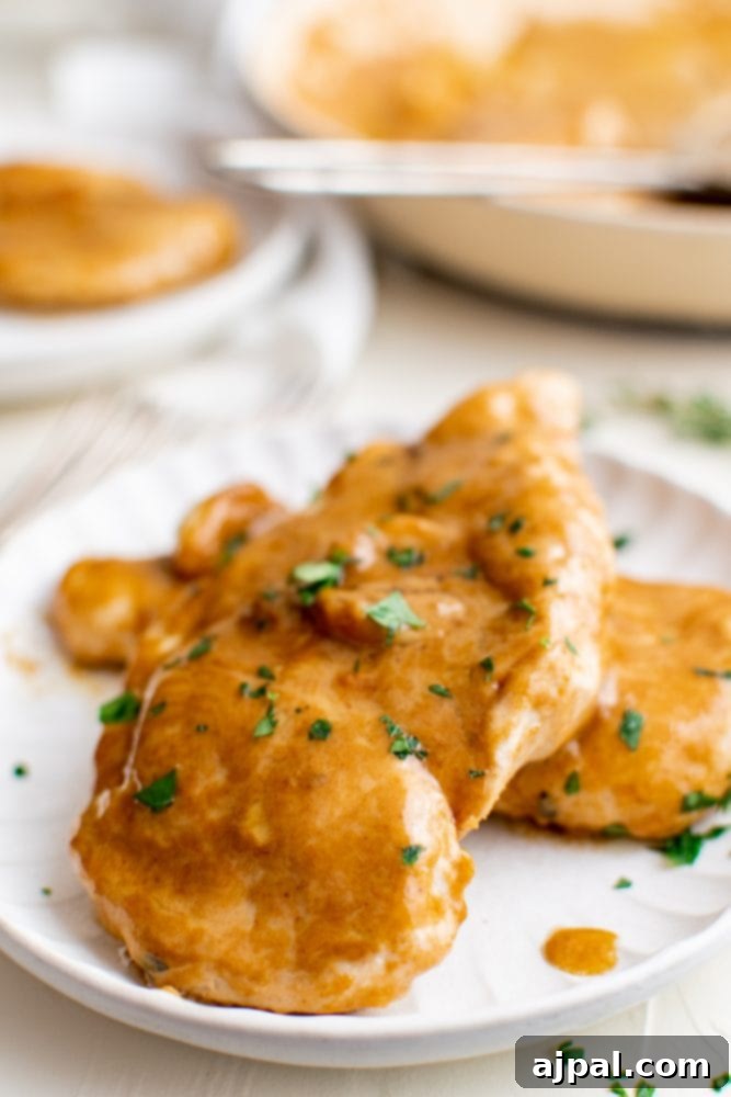 Creamy Garlic Chicken Made Simple 15 Creamy garlic chicken breasts on a pristine white plate, garnished with fresh parsley.