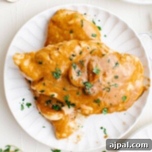 A plate with chicken covered in creamy garlic sauce.