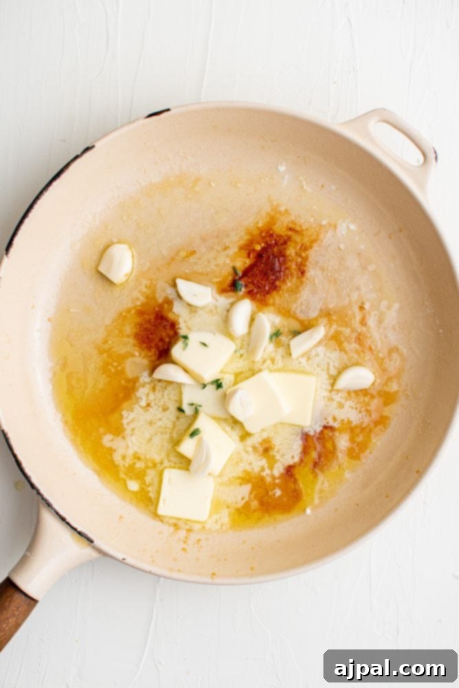 A frying pan filled with chicken cooking in creamy garlic sauce.