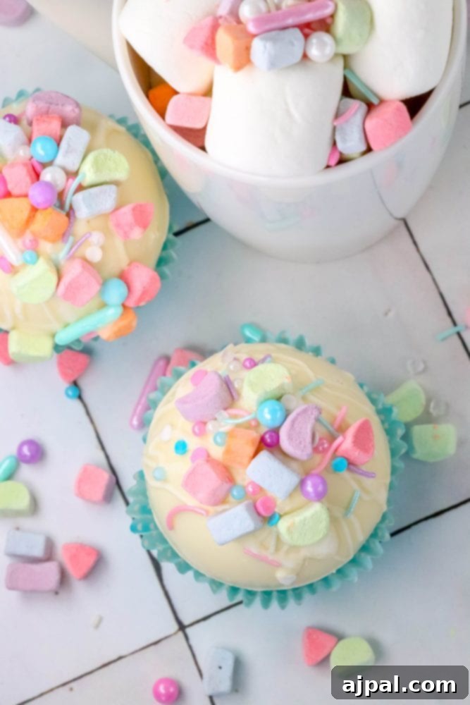 Magical White Chocolate Lucky Charms Bombs 7 white chocolate hot chocolate bomb in a blue cupcake wrapper with lucky charms marshmallows and sprinkles on top next to a mug with cocoa, sprinkles, and marshmallows in it