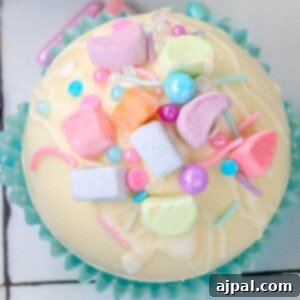 Magical White Chocolate Lucky Charms Bombs 9 white chocolate hot chocolate bomb in a blue cupcake wrapper with lucky charms marshmallows and sprinkles on top next to a mug