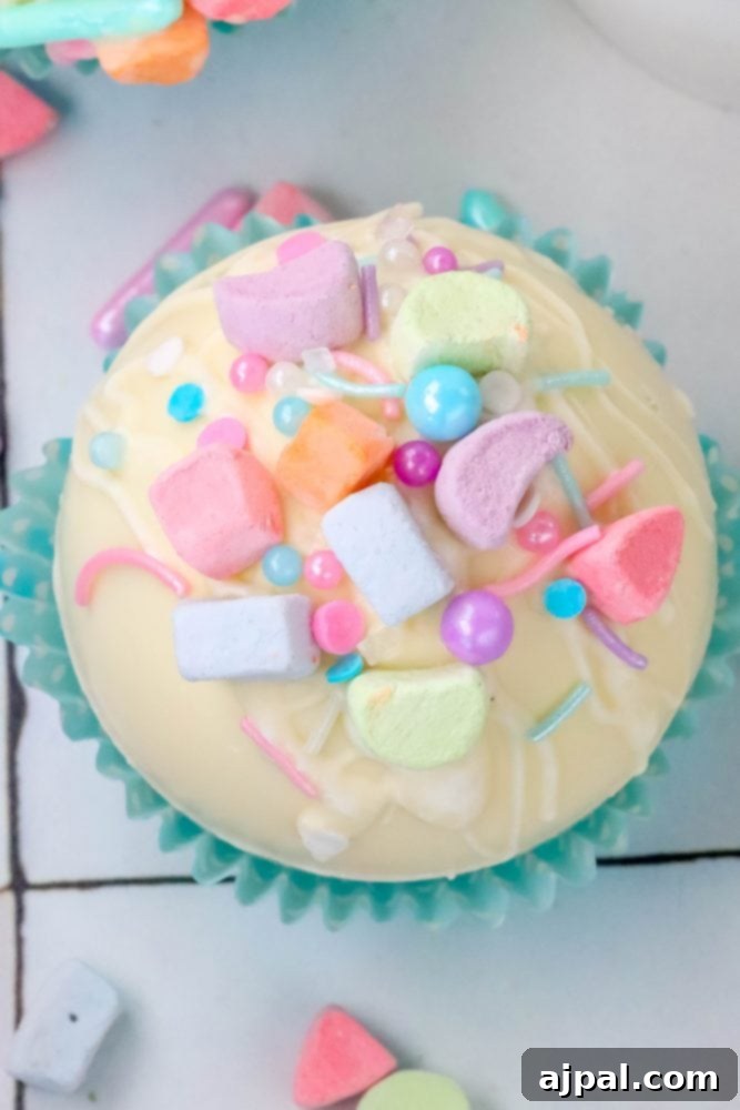 Magical White Chocolate Lucky Charms Bombs 3 white chocolate hot chocolate bomb in a blue cupcake wrapper with lucky charms marshmallows and sprinkles on top