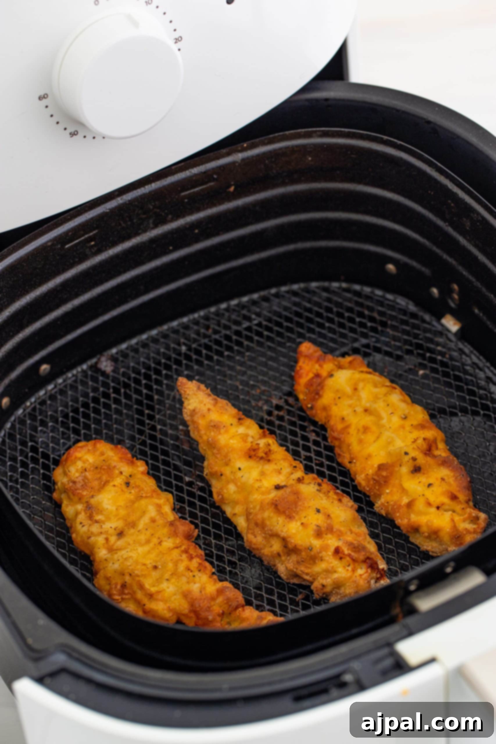 A close-up of a stack of golden, crispy air fryer chicken tenders.