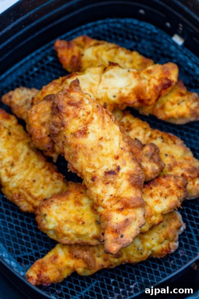 Freshly breaded chicken tenders perfectly arranged in an air fryer basket, ready for cooking.