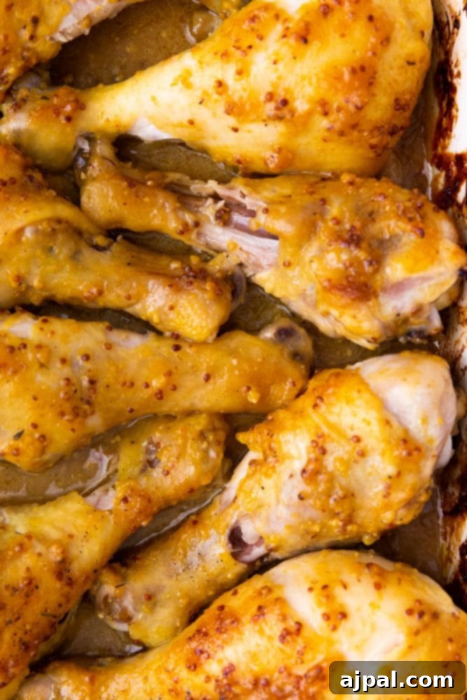 Glazed Honey Mustard Chicken Drumsticks 4 Honey mustard chicken drumsticks simmering in a baking dish, coated in golden sauce.