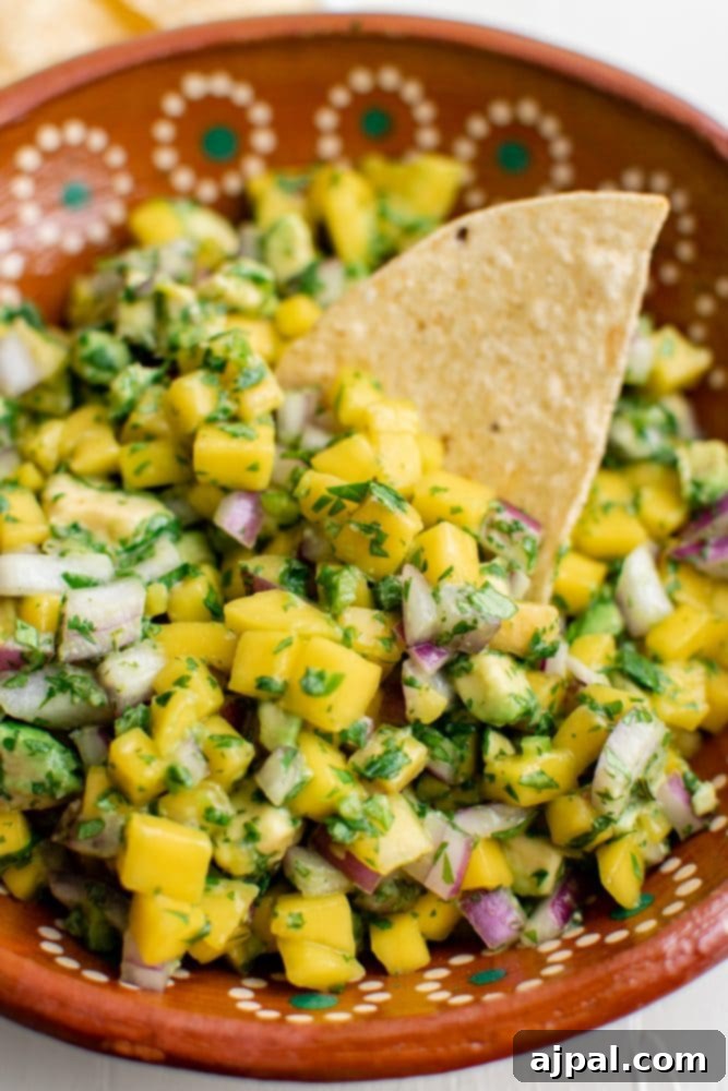 Tropical Mango Avocado Salsa 2 A colorful bowl of fresh mango avocado salsa with golden tortilla chips on the side, ready for dipping.
