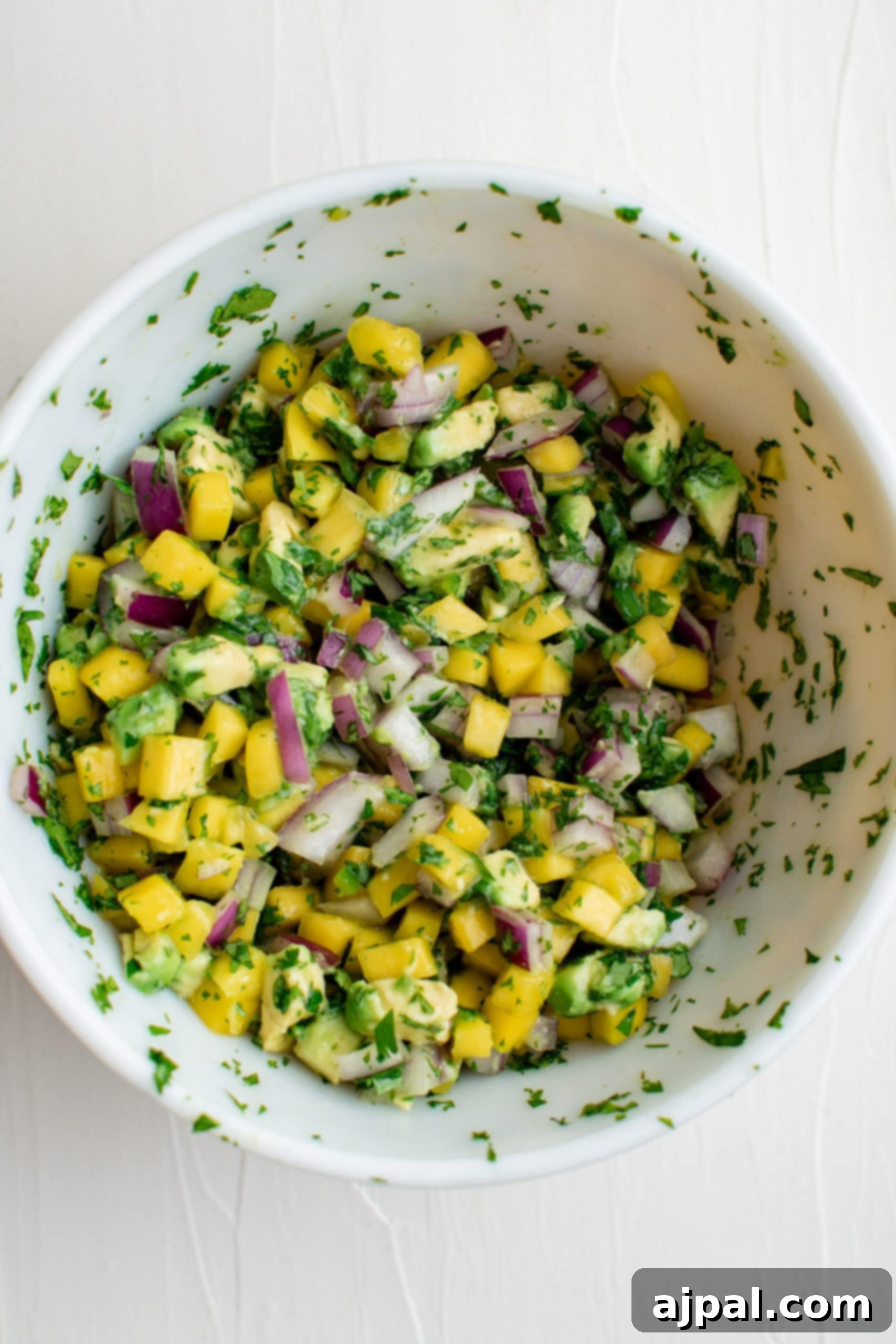Tropical Mango Avocado Salsa 8 Avocado salsa in a white bowl featuring an easy mango avocado salsa recipe.
