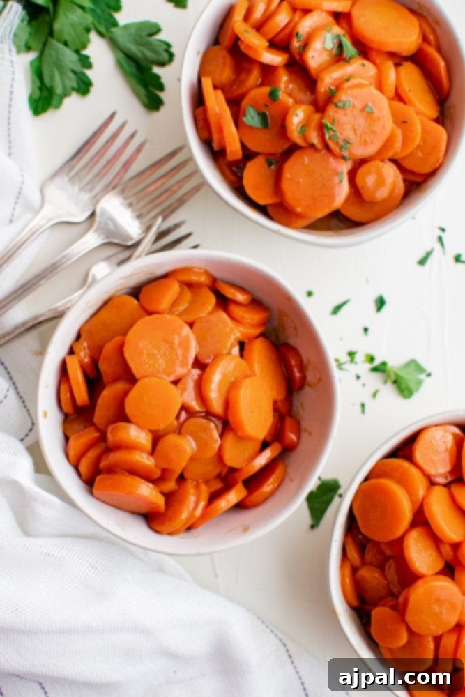 Picture of three bowls filled with vibrant sugar-glazed carrots, garnished with fresh parsley, and accompanied by forks.