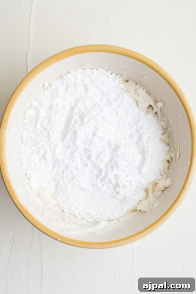 Effortless Rainbow Fruit Pizza 11 Powdered sugar being sifted into the cream cheese mixture for a silky smooth topping.