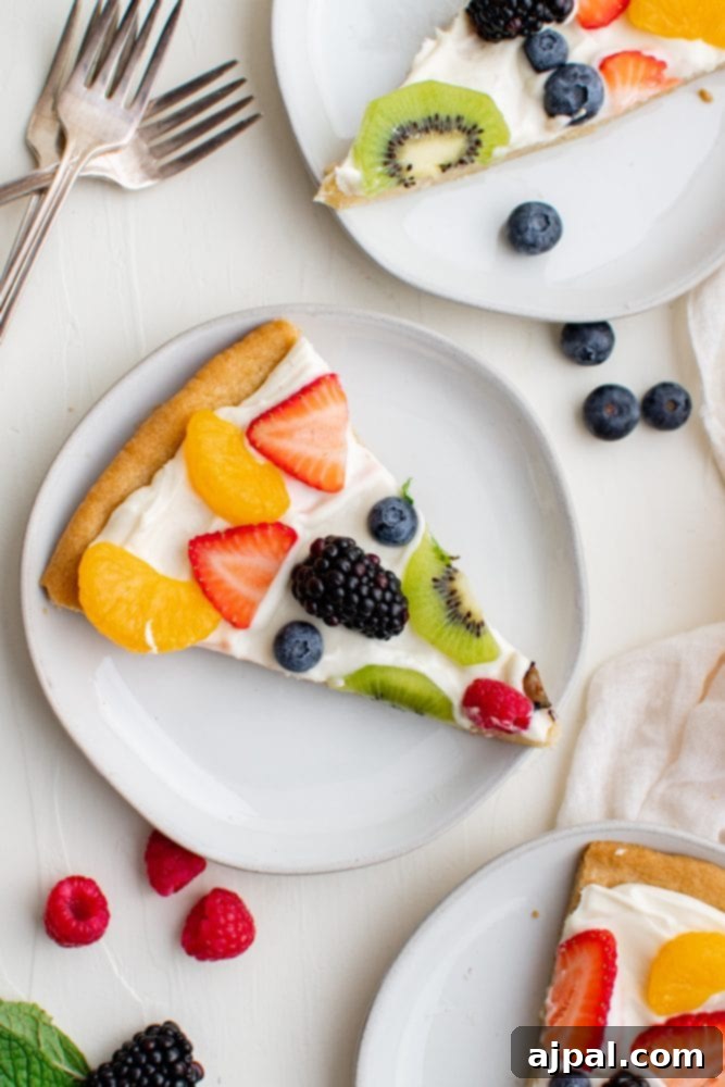 Effortless Fruit Pizza Perfection 14 Two vibrant slices of fruit pizza on a white plate, showcasing a delightful arrangement of fresh berries and kiwi over a creamy topping and crisp cookie crust.