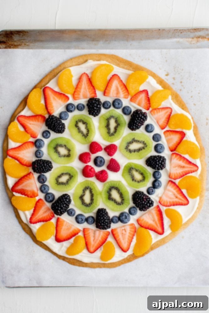 Effortless Fruit Pizza Perfection 16 A vibrant fruit pizza, artfully arranged with concentric circles of fresh berries, kiwi, and mandarin oranges on a creamy base.
