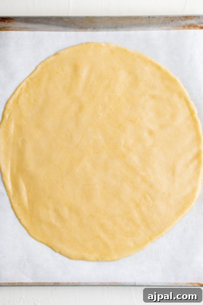 Effortless Fruit Pizza Perfection 6 Raw cookie dough, perfectly rolled out into a large, even circle on parchment paper, ready for baking.