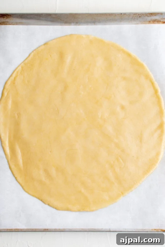 Effortless Rainbow Fruit Pizza 6 Raw sugar cookie dough rolled out into a perfect circle on baking paper, ready for the oven.