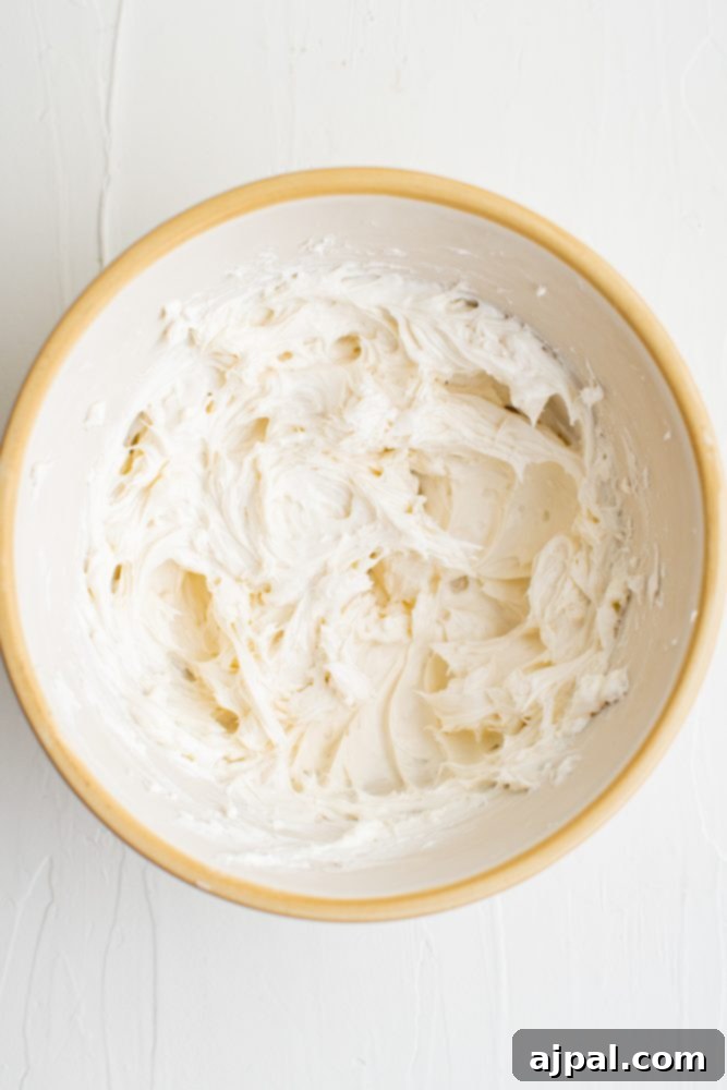 Effortless Fruit Pizza Perfection 10 A smooth, white cream cheese mixture in a bowl, perfectly blended and ready for the addition of powdered sugar.
