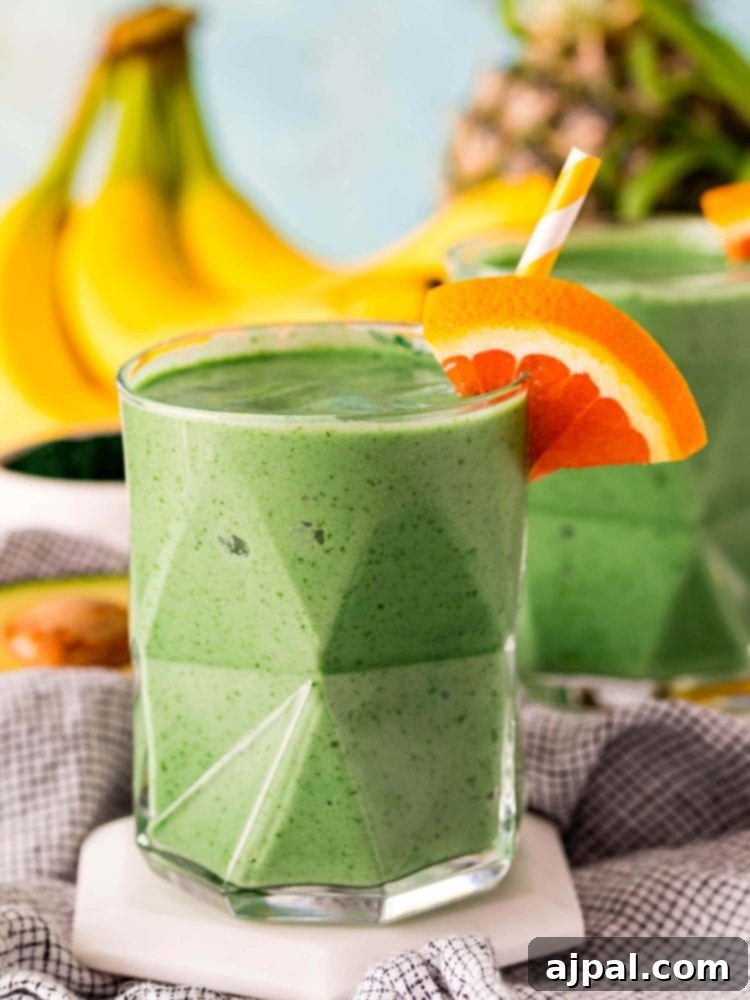 Sunshine Green Smoothie Boost 2 Two glasses of green smoothie with orange slices and bananas.