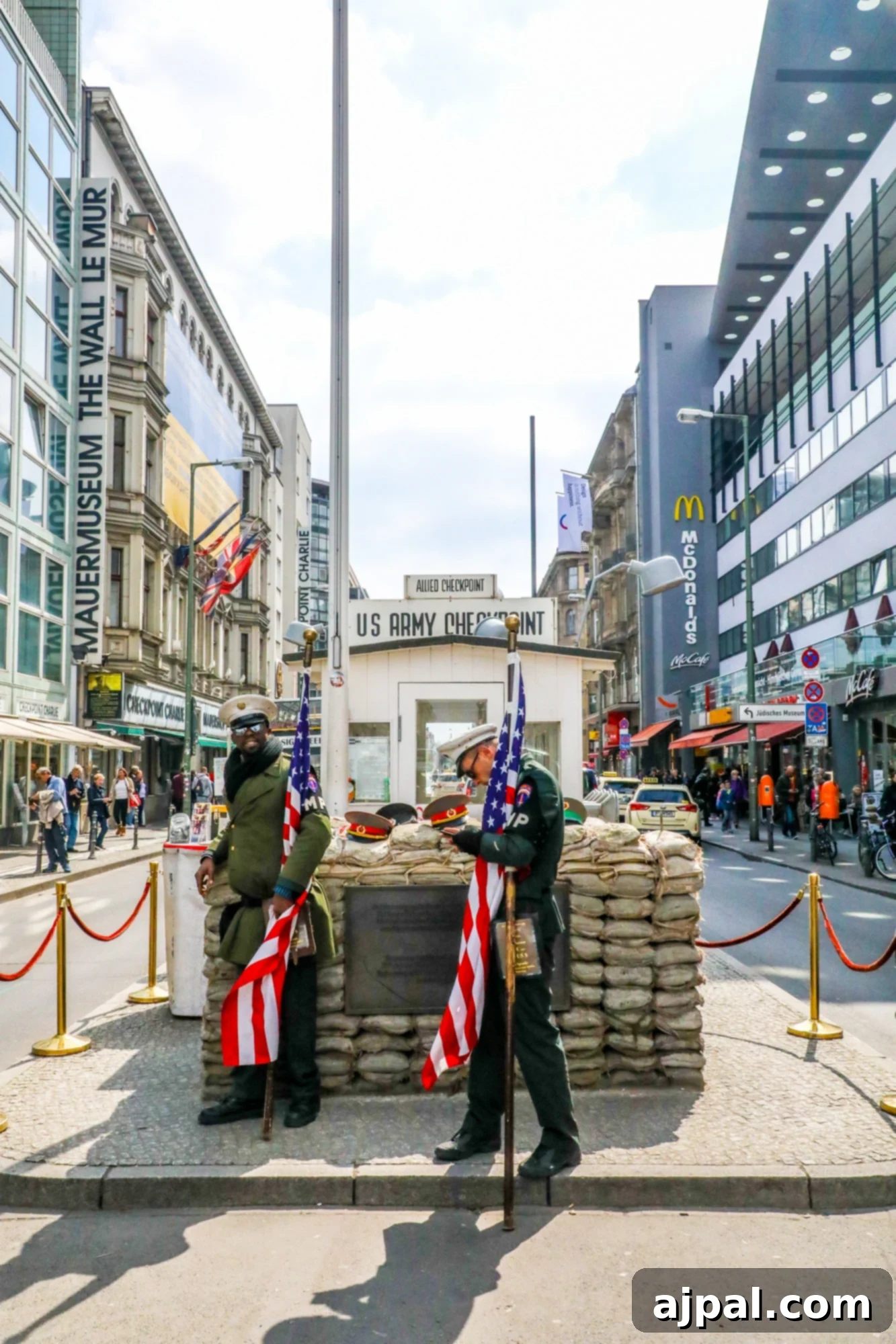 Two historical reenactors standing in front of sandbags at Checkpoint Charlie in Berlin.