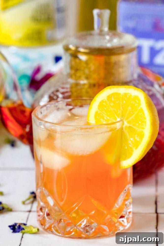 Bubbly Earl Grey Tea Tonic 2 A vibrant Earl Grey Sparkling Tea and Tonic Mocktail in a glass with lemon, a teapot in the background.