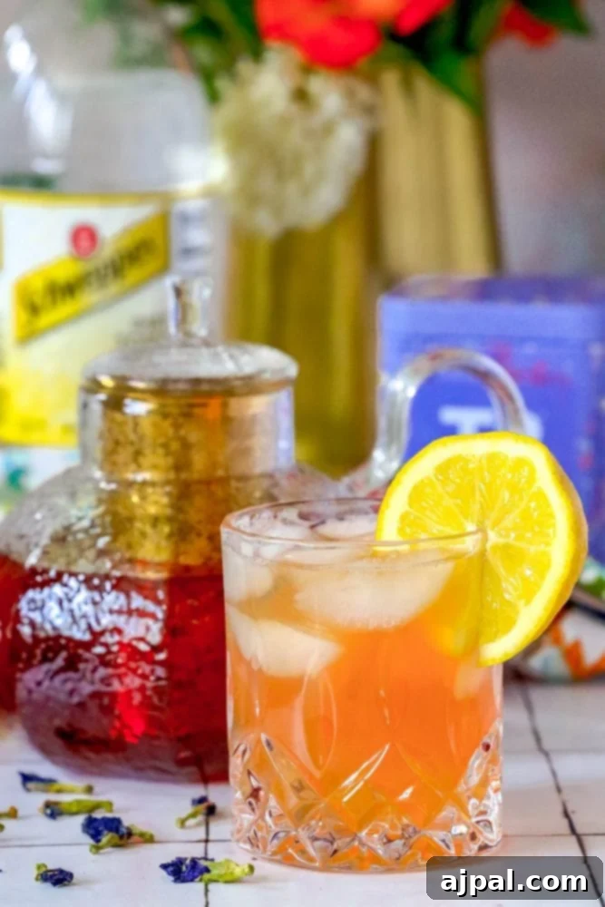 Sparkling Earl Grey Tonic Recipe 5 A perfectly chilled glass of Earl Grey Sparkling Tea and Tonic with a slice of lemon, next to a beautifully designed teapot, inviting a moment of refreshing indulgence.