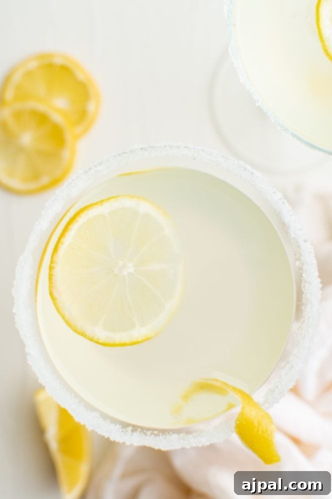 Zesty Lemon Drop Martini Recipe 9 light yellow drink with sliced lemon and salt around the rim