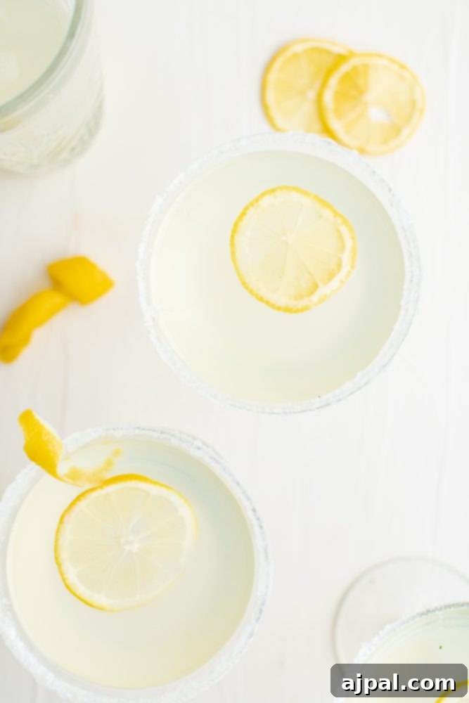Zesty Lemon Drop Martini Recipe 3 light yellow drink with sliced lemon and salt around the rim