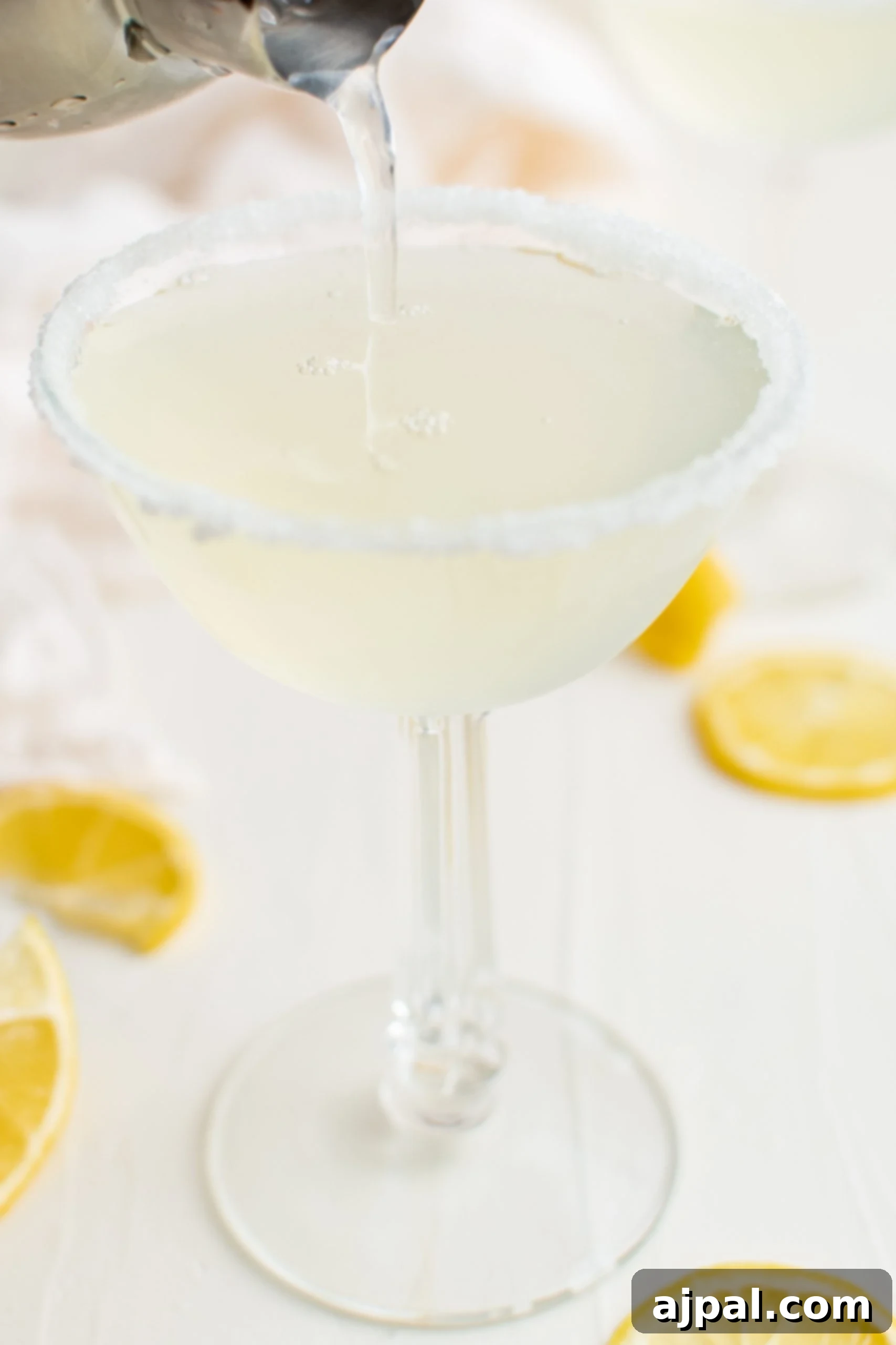 A Lemon Drop Martini being expertly poured into a sugar-rimmed glass, ready to be enjoyed.