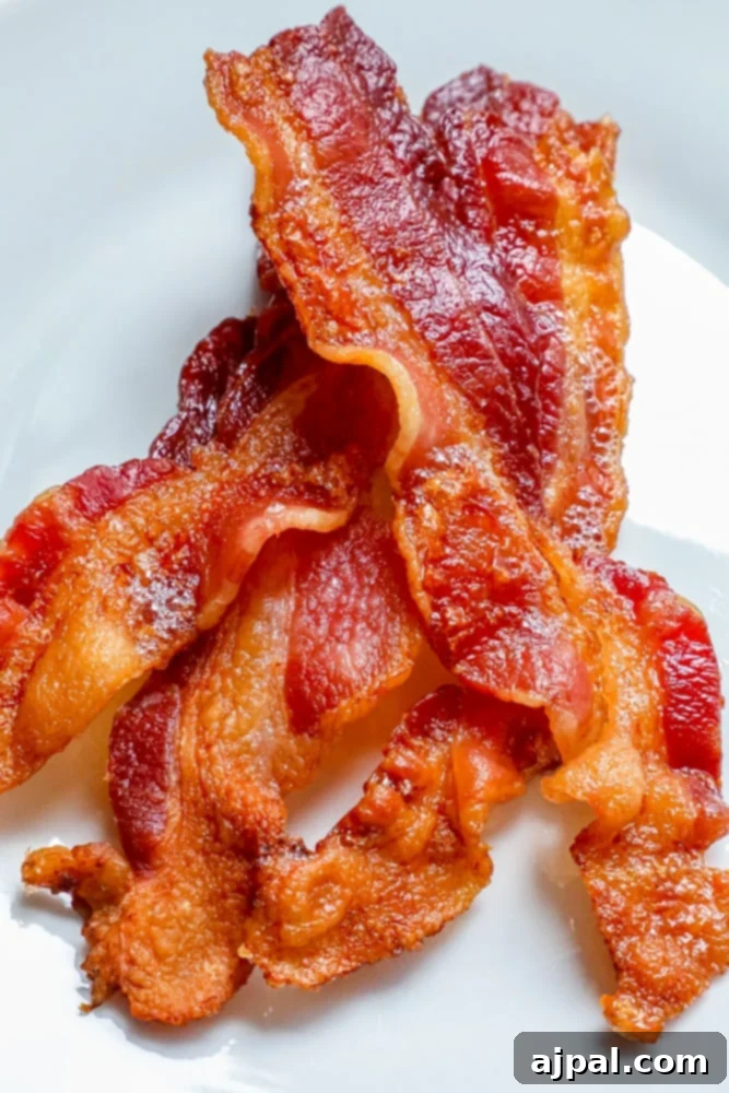 Crispy oven-baked bacon strips perfectly cooked and arranged on a plate.