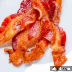 A close up of bacon baked in the oven on a white plate.
