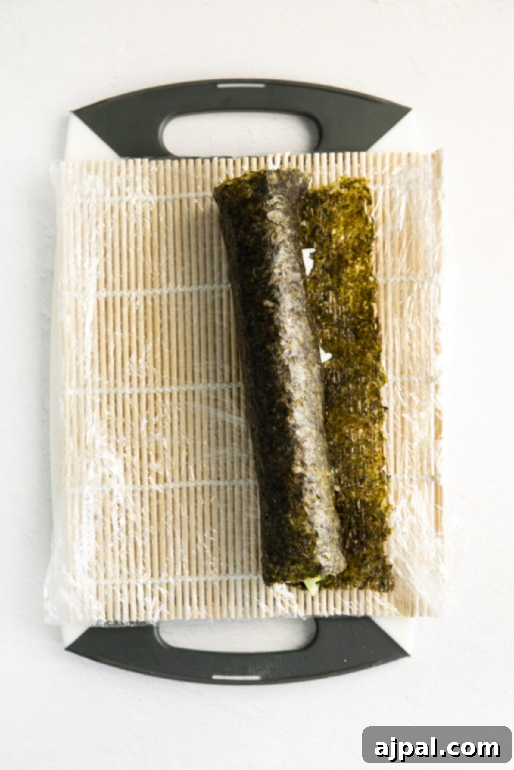 A freshly rolled, uncut log of vegan sushi rests on a cutting board, ready for slicing.
