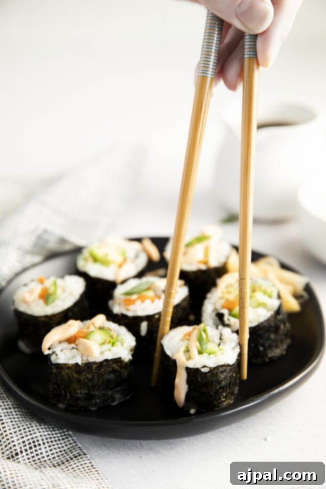 A person is holding chopsticks over a plate of beautifully arranged easy vegan sushi, ready to be enjoyed.