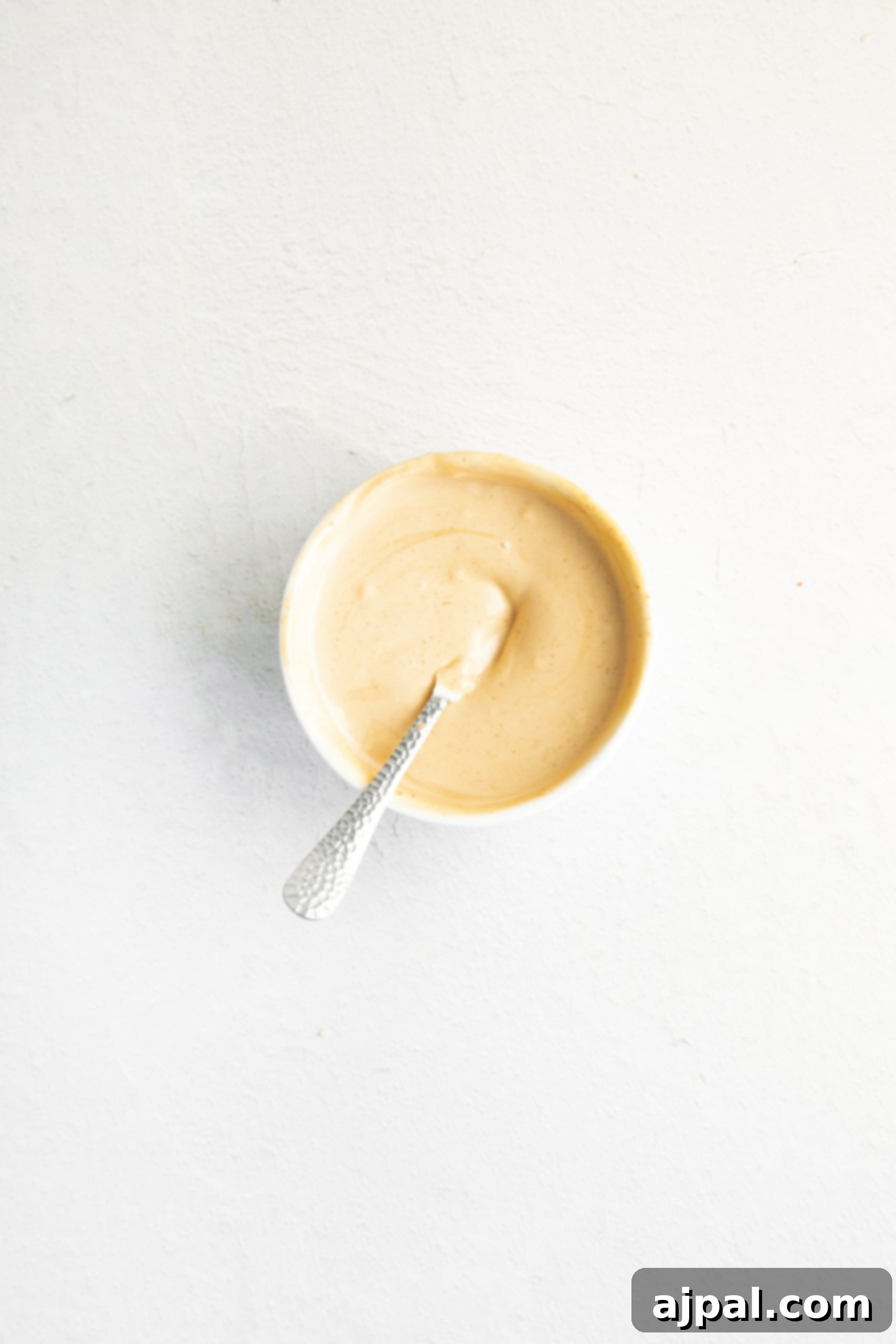 A bowl of creamy, orange-hued spicy vegan mayo, ready to be served.