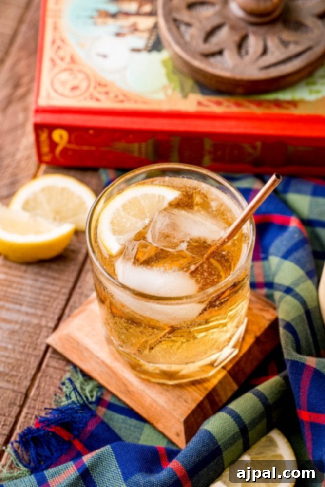 A glass of scotch whisky on a table paired with a book, suggesting a moment of relaxation.