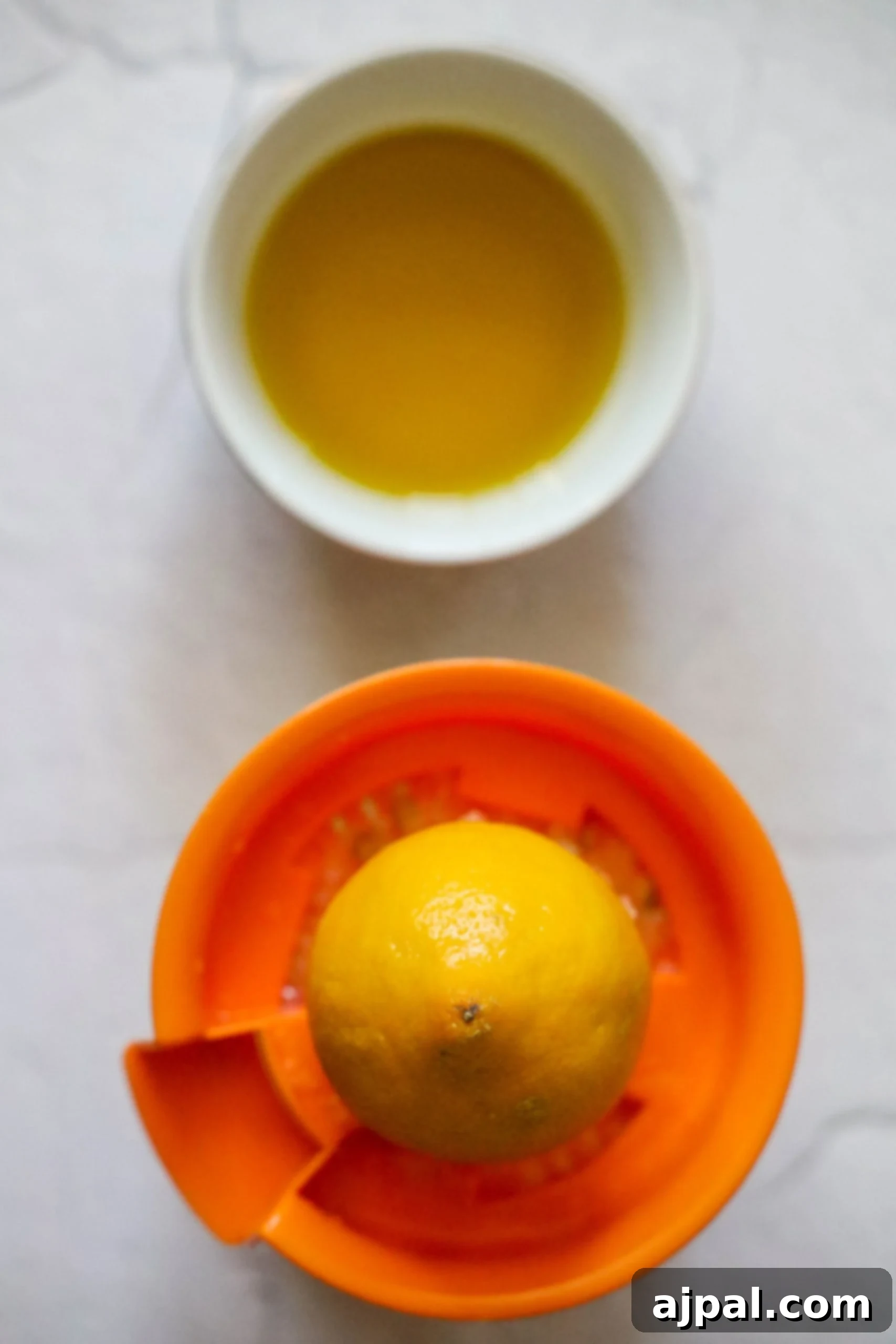 Picture of lemon half on a juicer with a bowl of olive oil, highlighting the dressing components.