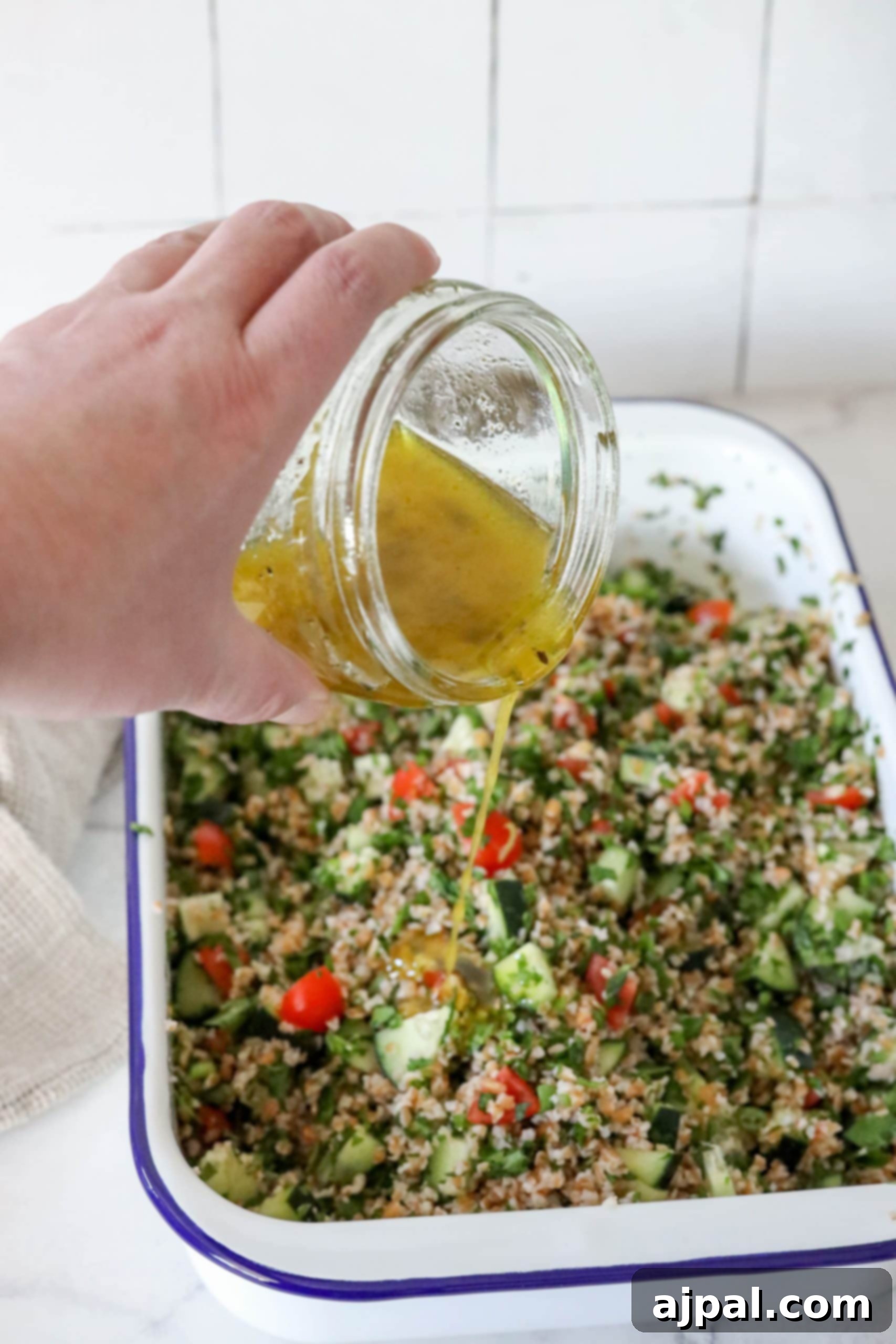 picture of hand pouring olive oil and juice over tabbouleh