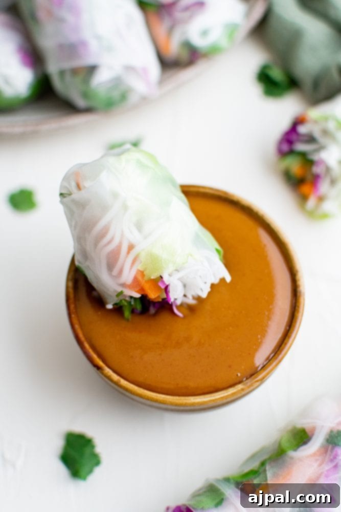 Creamy Peanut Dip in Minutes 3 A crisp spring roll being dipped into a rich, creamy peanut sauce, highlighting its appetizing appeal.