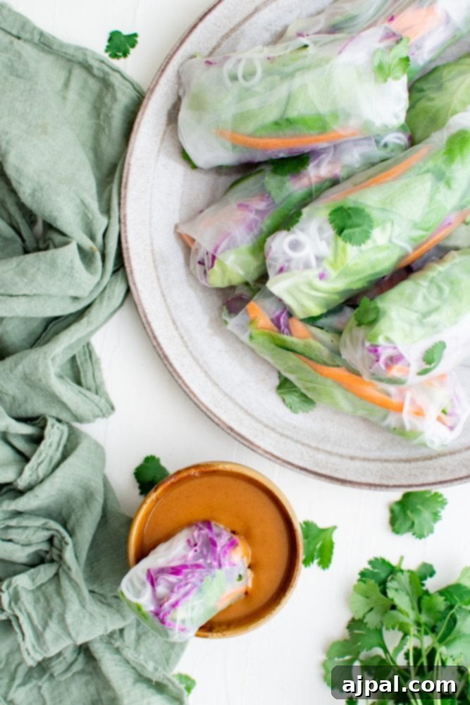 Creamy Peanut Dip in Minutes 4 A freshly made spring roll is held above a bowl of creamy peanut dipping sauce, ready to be enjoyed.