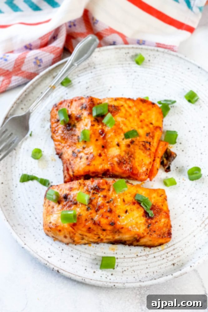 Easy Air Fryer Jerk Salmon 2 Perfectly air-fried jerk salmon fillets, garnished with fresh green onions, served on a white plate.