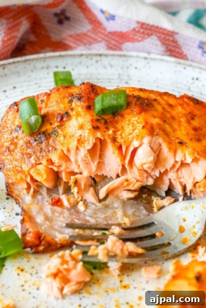 Easy Air Fryer Jerk Salmon 3 A delicious serving of air-fried jerk salmon, partly eaten, on a white plate with a fork.