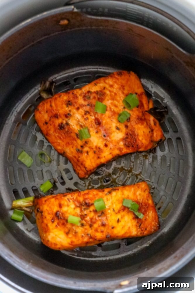 Easy Air Fryer Jerk Salmon 9 A close-up of spicy salmon fillets cooking in an air fryer basket, perfectly crispy.