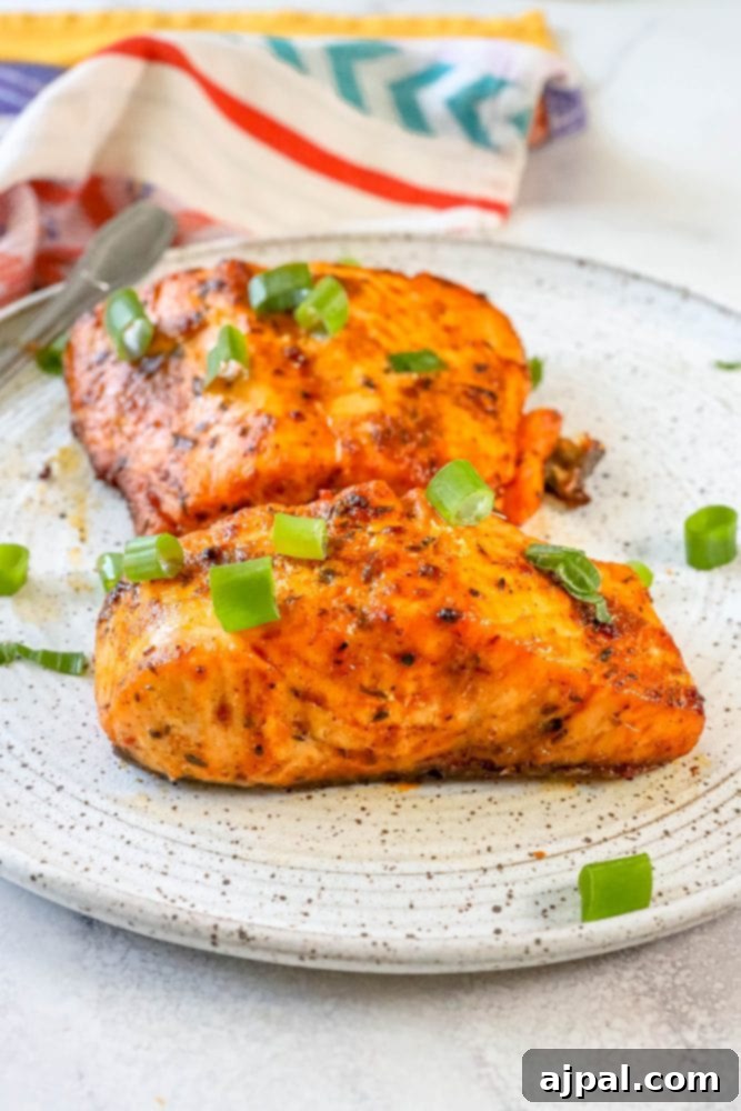 Easy Air Fryer Jerk Salmon 4 Two servings of air-fried jerk salmon, garnished with green onions, presented on a white plate.