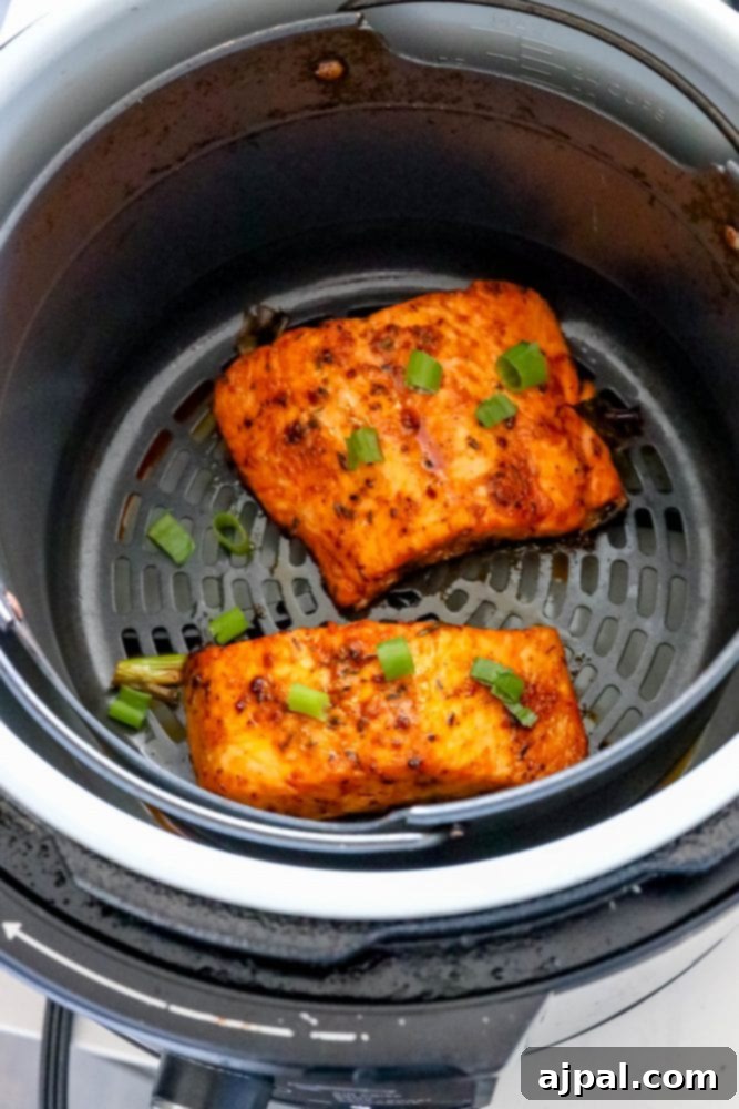Easy Air Fryer Jerk Salmon 6 Spicy jerk salmon cooked to perfection in an air fryer basket, garnished with green onions.