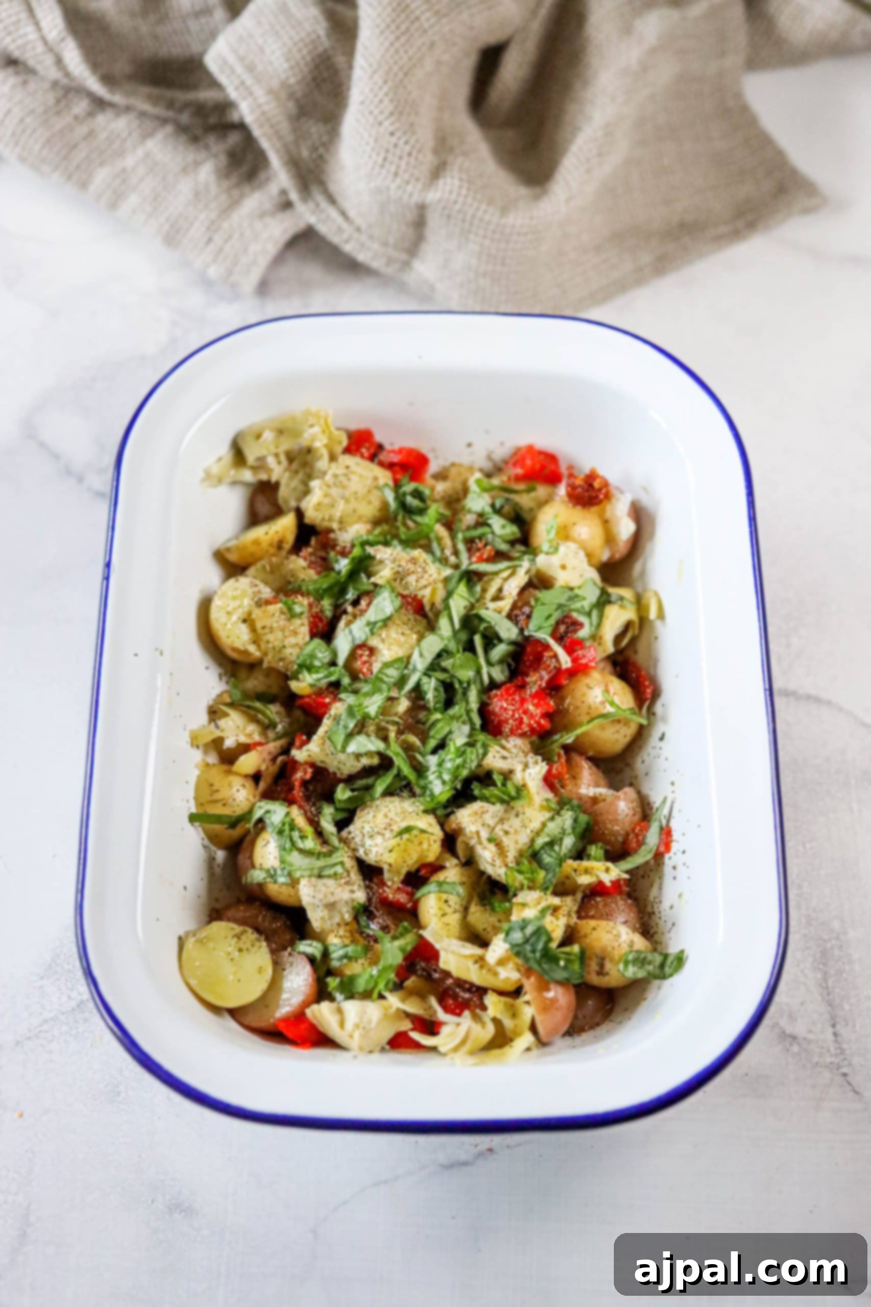 Zesty Italian Potato Salad 9 A vibrant serving platter showcasing an Italian Potato Salad, featuring tender potatoes, fresh basil, succulent roasted red pepper strips, marinated artichoke hearts, and sun-dried tomatoes.