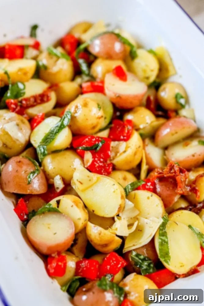 Zesty Italian Potato Salad 4 A delectable vegan Italian potato salad, visually appealing with its blend of golden potatoes and colorful roasted red peppers, resting in a stylish white dish.